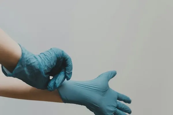 Hands putting on blue medical gloves