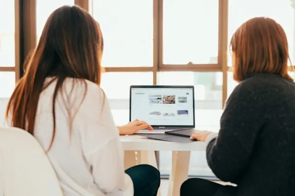 Two women talking in front of a laptop